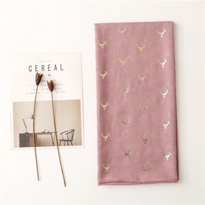 Detail of pink scarf with golden deer print next to a magazine and dried flowers
