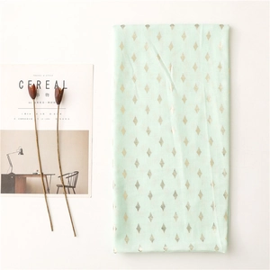 Detail of light green scarf with gold diamond print and stylish lifestyle accessories