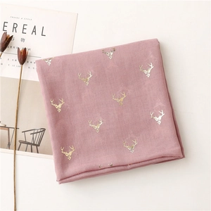 Detailed macro view of lotus pink scarf with metallic gold reindeer prints and soft texture