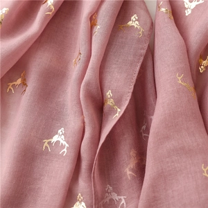 Close-up of pink scarf featuring fine fabric texture and gold foil deer pattern