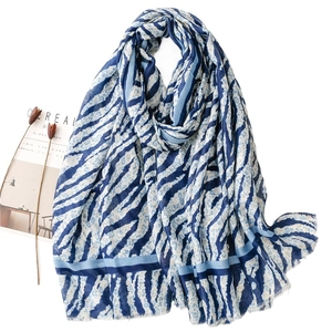 Blue and white tiger striped scarf with frayed tassels on a minimalist white background
