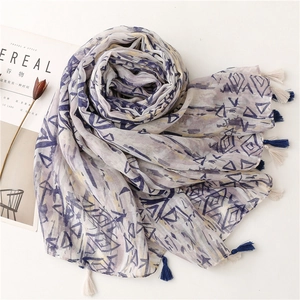 Detailed view of lightweight gray scarf featuring geometric blue prints and soft tassels