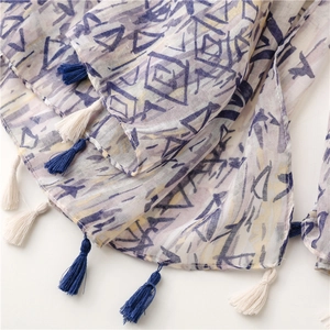 Detail of geometric print scarf with dark blue tassels and light textured fabric