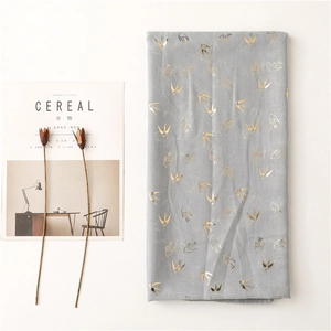 Detail of grey lightweight scarf with gold foil swallow print and natural fabric texture