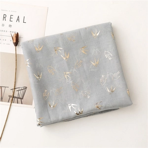 Detail of light gray cotton scarf with gold and silver swallow foil print motifs