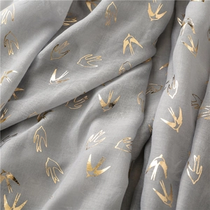 Close-up of lightweight grey scarf with metallic gold swallow bird foil print detail