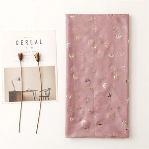 Close-up of pink cotton-linen scarf with gold foil swallow prints and texture
