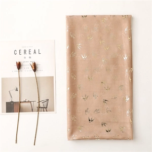 Detail showing gold swallow pattern on pinkish lightweight scarf with lifestyle magazine