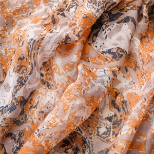 Detail eines Schals mit Marmordruck, orange-blauen Tintenmustern und weichen Fransen