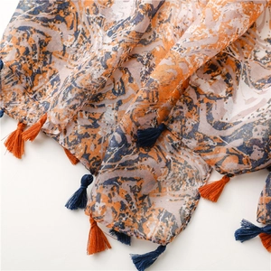 Detail eines kunstvollen Marmor-Druck-Schals mit weichen Quasten in Orange und Blau