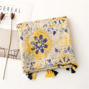 Detail of soft scarf with yellow and blue geometric snowflake patterns and tassels