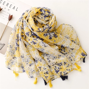 Detail of yellow and navy blue abstract floral scarf with fringe tassels on white background