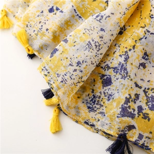 Detail of yellow and blue abstract print scarf featuring soft cotton-linen texture and tassels