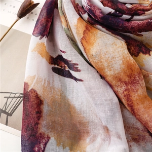 Detailed macro view of the ethnic floral linen-feel scarf with artistic sunset orange print