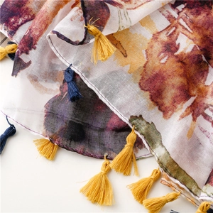 Detail of colorful ethnic floral print scarf featuring delicate tassels and soft fabric
