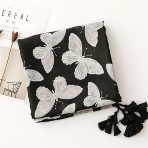 Detail of black scarf with white butterfly prints and soft fringe tassels on a table