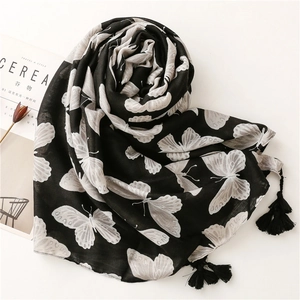 Detail of black and white butterfly pattern scarf with fine tassel edges on a white surface