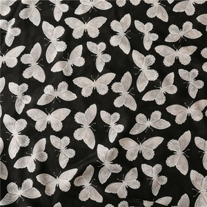 Close-up of black herringbone cotton linen scarf with detailed white butterfly print pattern