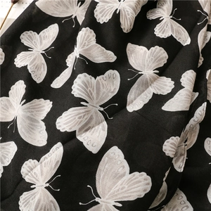 Detailed view of black herringbone weave fabric with white butterfly print patterns