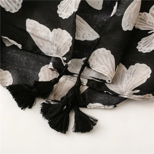 Detail of herringbone linen scarf featuring white butterfly prints and black tassels