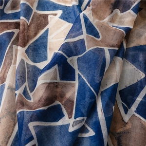 Macro view of geometric pattern scarf showing translucent fabric texture and tassel detail