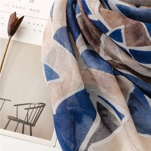Detail of geometric pattern scarf with blue and beige block print and fringe edges