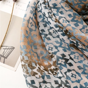 Detail of geometric floral scarf showing light chiffon texture and soft blue-brown patterns