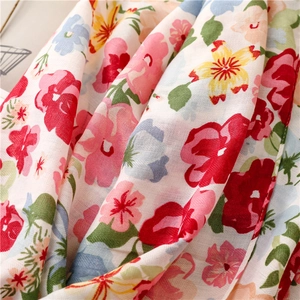 Gros plan d'une écharpe en coton et lin à fleurs montrant la texture douce et les motifs