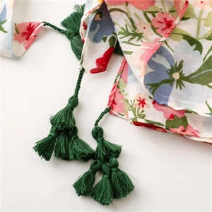 Détail d'une écharpe en lin à motifs floraux et pampilles à franges vert foncé