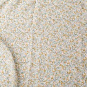 Macro detail of floral print voile scarf featuring light blue and orange blossom patterns