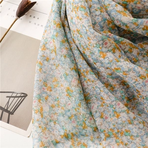 Close-up of floral print cotton linen scarf featuring soft pastel petals and fringe tassels