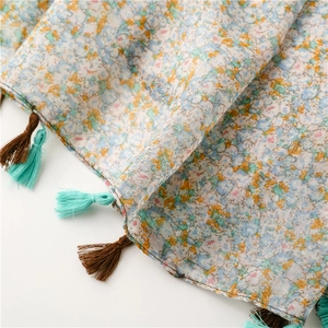 Detail of floral printed scarf with colorful tassels and breathable cotton linen texture