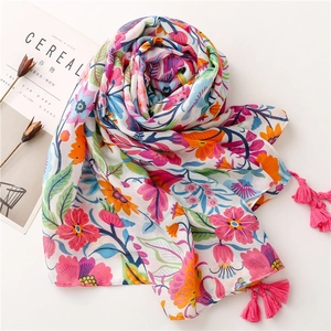 Detailed view of colorful floral print shawl with vibrant pink tassels on white background