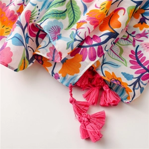 Detail of colorful floral cotton scarf with bright pink tassels and herringbone texture