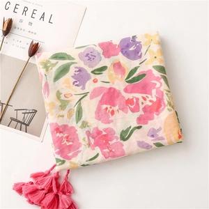 Detail of tropical flower print on a lightweight scarf with decorative pink fringe tassels