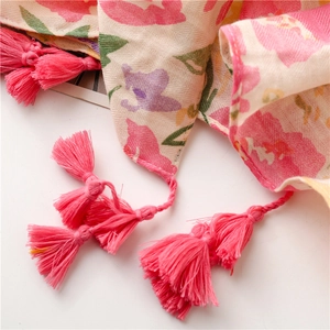 Close-up of tropical floral scarf with pink tassels and herringbone cotton linen texture