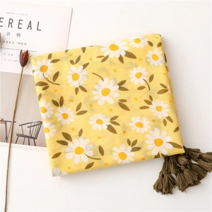 Detail of yellow herringbone scarf with white daisy prints and green tassels