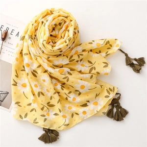 Detail of lemon yellow cotton scarf with daisy print and elegant green tassels