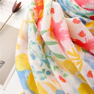Detailed view of colorful floral print scarf showing herringbone weave and tassel texture