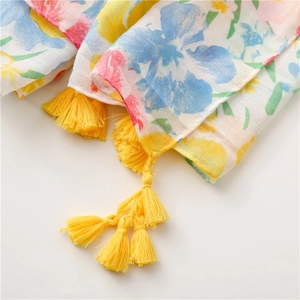 Detailed macro view of tropical floral print scarf with bright yellow fringe tassels