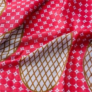 Nahaufnahme eines rot-weiß gepunkteten Schals mit braunem geometrischem Gitter
