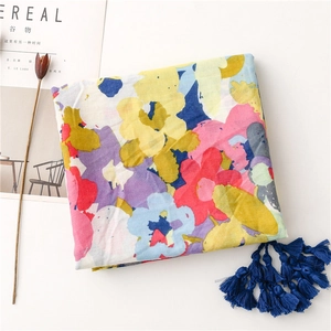 Detail of colorful floral cotton scarf with long navy blue tassels on white background