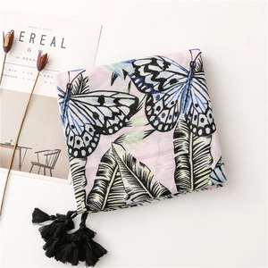 Detail of pink cotton linen scarf with blue butterfly prints and black tassel edges