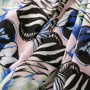 Macro detail of tropical plant print on breathable linen-feel fabric with butterfly pattern