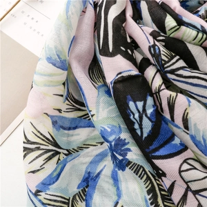 Close-up of tropical leaf print on herringbone textured fabric with fringe details