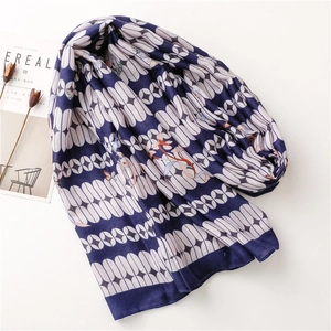 Navy blue scarf with white geometric patterns and orange floral accents and fringe