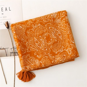 Detail of orange paisley cotton scarf featuring intricate patterns and soft fringe tassels