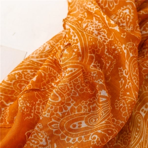 Detailed macro view of orange linen-feel scarf with white paisley pattern and texture