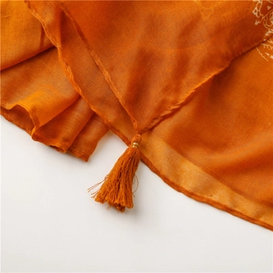 Close-up of orange cotton-linen scarf with white paisley print and fringe tassels