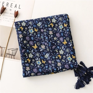 Detail of navy blue cotton linen scarf featuring floral butterfly patterns and fringe